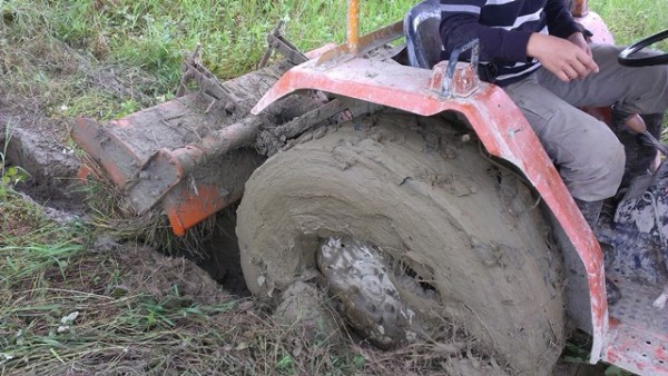 休耕十多年後，第一次整地就接連「着車」三次，曳引機的大輪陷入軟土內沾滿泥濘。