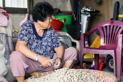 在路上村街上，隨處可見高齡農民坐在地上剝花生。（劉喜豪提供）