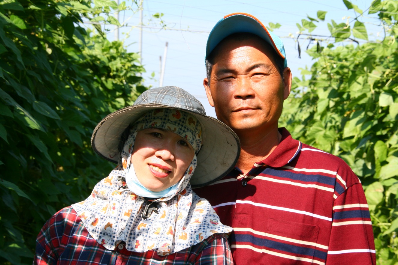 1-跟先生一起站在敏豆園裡合照，阿枝在屏東高樹找到務農的自信。她說每次回到越南，都會有人跑來家裡請教她如何務農。-1326